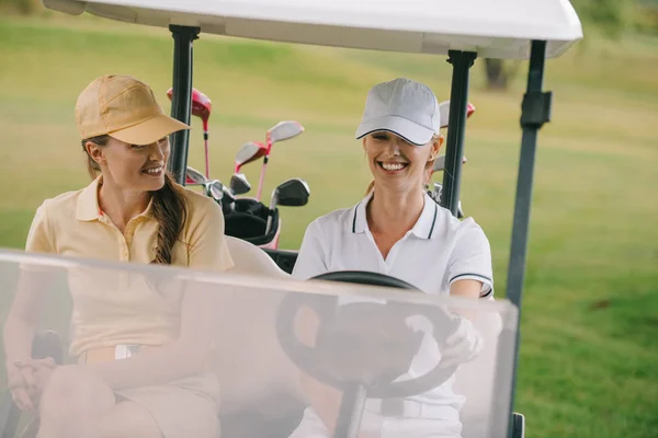 ゴルフ場のゴルフカートに乗って笑顔の女性ゴルフ選手  — 無料ストックフォト