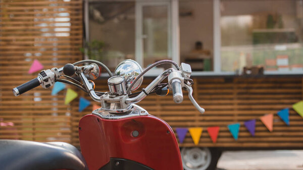 close-up view of red scooter and food truck with colorful flags behind  
