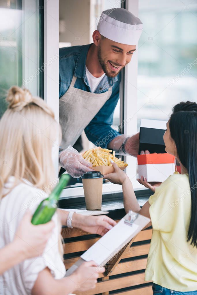 happy chef giving french fries to customer from food truck