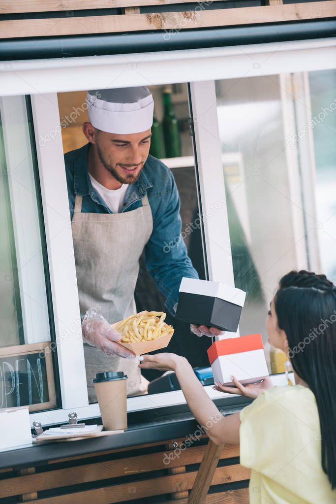 chef giving french fries to customer from food truck
