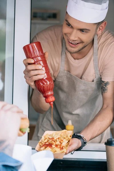 笑顔のシェフのフード トラックのホットドッグにケチャップを追加します — ストック写真