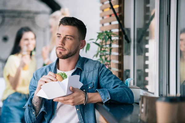 Όμορφος Άνδρας Κρατώντας Burger Και Αναζητούν Μακριά Κοντά Στο Φορτηγό — Φωτογραφία Αρχείου