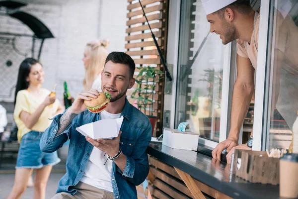 Przystojny Mężczyzna Jedzenie Kuchnia Burgery Pobliżu Food Trucka — Zdjęcie stockowe