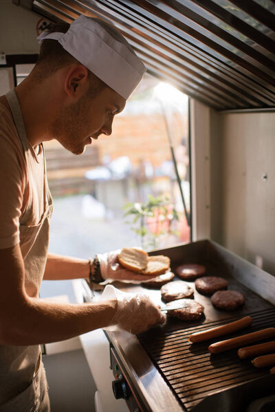 side view of chef preparing burgers in food truck