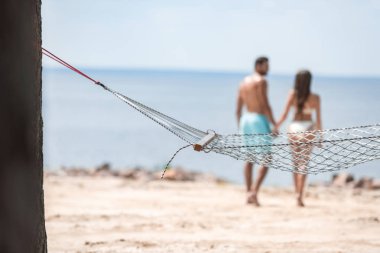 seçici odak elele ve ön plan hamak ile sahilde yürüme çift