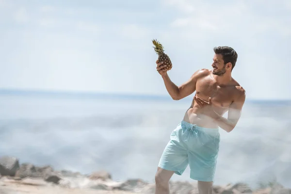 Hombre Alegre Mirando Piña Fresca Playa Enfoque Selectivo —  Fotos de Stock