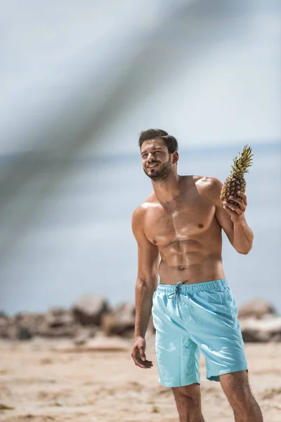 Ευτυχισμένος Άνθρωπος Shirtless Κρατώντας Ανανά Στην Παραλία Της Θάλασσας — Δωρεάν Φωτογραφία