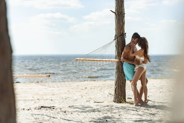 两个游客在海滩上抱着吊床靠近海边 — 图库照片