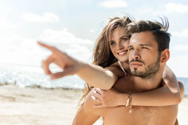 Homem Piggybacking Sua Namorada Enquanto Ela Apontando Praia — Fotografia de Stock