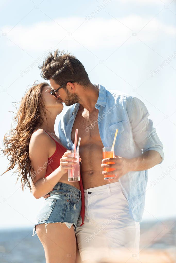 happy couple kissing and holding alcohol cocktails 
