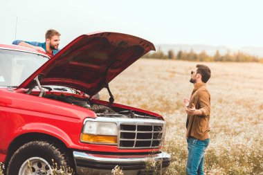 Genç erkekler alanındaki kırık motoru ile arabanın yakınında duran