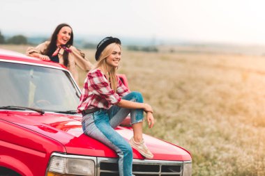 happy young girlfriends having car trip and looking at beautiful nature clipart