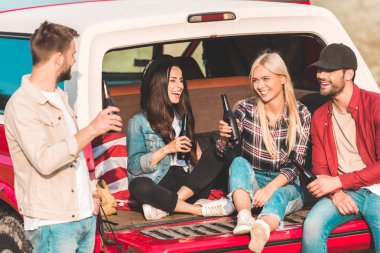 bira içip araba gövde doğa üzerinde otururken chat yapan gençlerin Grup