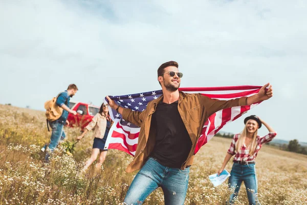 Bonito Jovem Segurando Eua Bandeira Andando Campo Com Amigos Durante — Fotografia de Stock