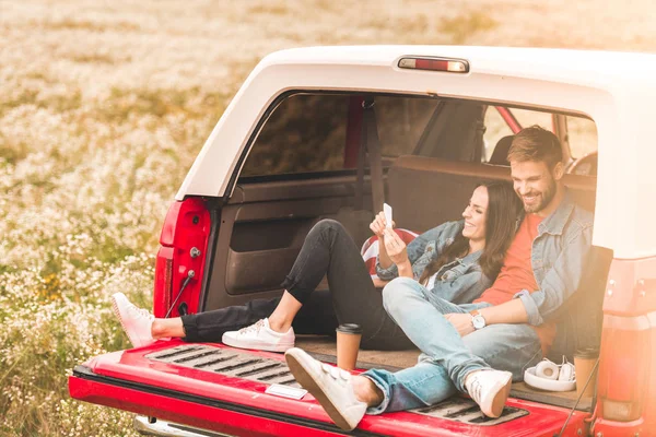 Belo Jovem Casal Usando Smartphone Enquanto Relaxa Porta Malas Carro — Fotografia de Stock