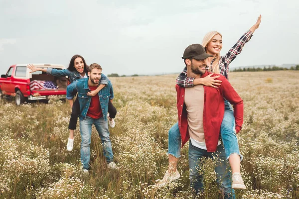 Fiatal Boldog Piggybacking Barátok Integetett Virág Mező Autó Utazás Során — Stock Fotó