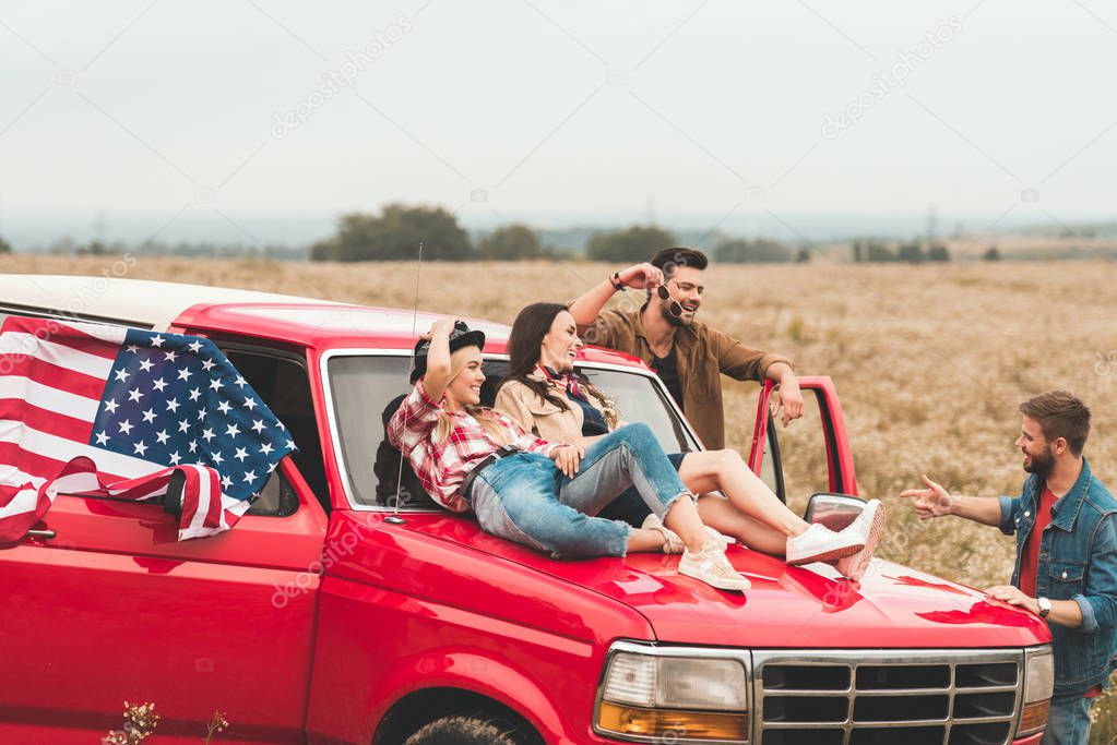 group of young american car travellers relaxing in flower field