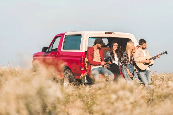 Grupo Jovens Amigos Bebendo Cerveja Tocando Guitarra Enquanto Sentado Carro — Fotografia de Stock