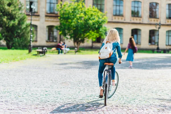 后视图的学生背包骑自行车在街上 — 图库照片