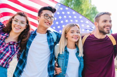 portrait of smiling multicultural students with american flag in park clipart