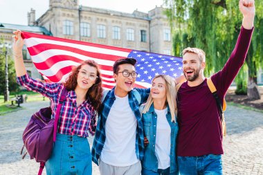 portrait of smiling multicultural students with american flag in park clipart