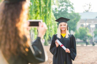 Mezuniyet university yakınındaki sırasında gülümseyen sınıf arkadaşı kadın alarak resmin kısmi görünümü