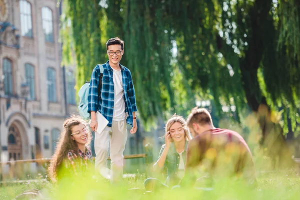 背景に大学と公園で休んでいる多民族の学生 — ストック写真