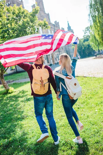 公園で手をつないでアメリカ国旗とカップルの背面します — ストック写真