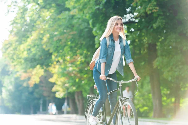 微笑的学生背包骑自行车在街上 — 图库照片