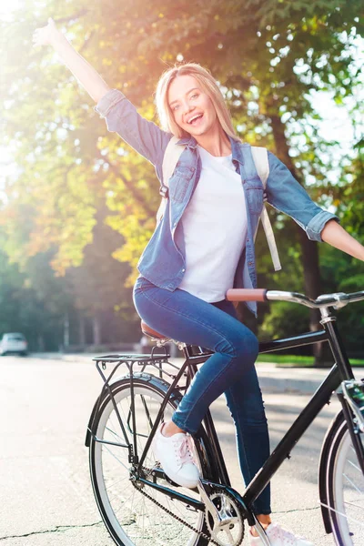 快乐的学生与背包手势 而骑自行车在街上 — 图库照片