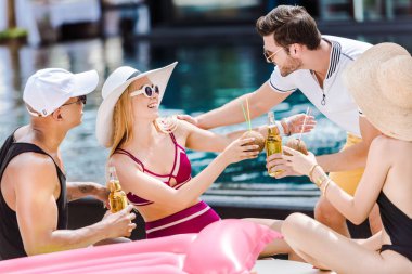 yüzme havuzu yanında bira ve Hindistan cevizi kokteyller ile tungur arkadaşlar gülümseyen