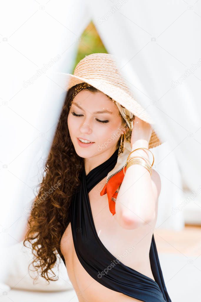 portrait of attractive girl with closed eyes touching hat