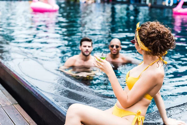 Chica Sentada Piscina Mirando Los Amigos Varones Nadando Piscina — Foto de Stock