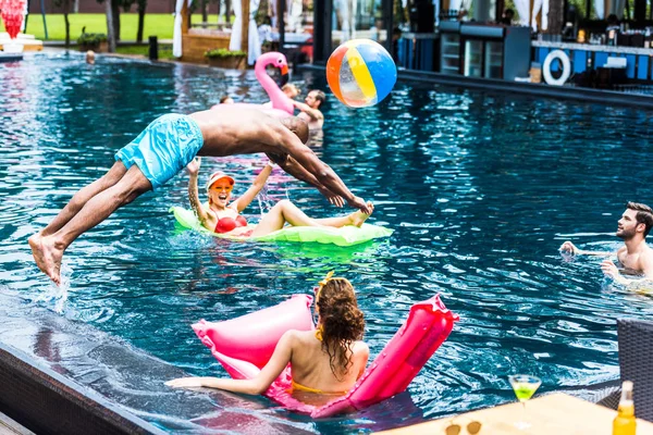 Young Man Jumping Swimming Pool While His Female Friends Resting — Stock Photo, Image