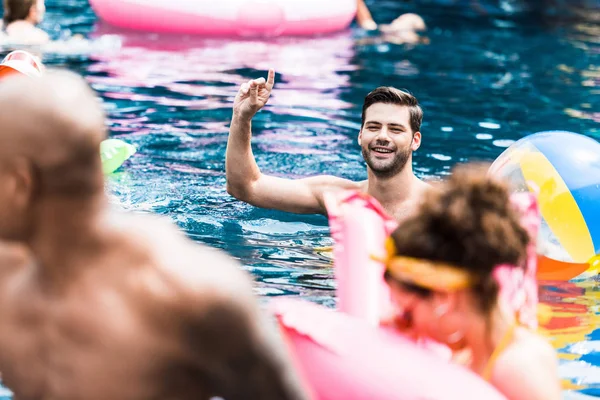 Glimlachende Man Met Opgeheven Vinger Zwembad Praten Met Vrienden — Stockfoto