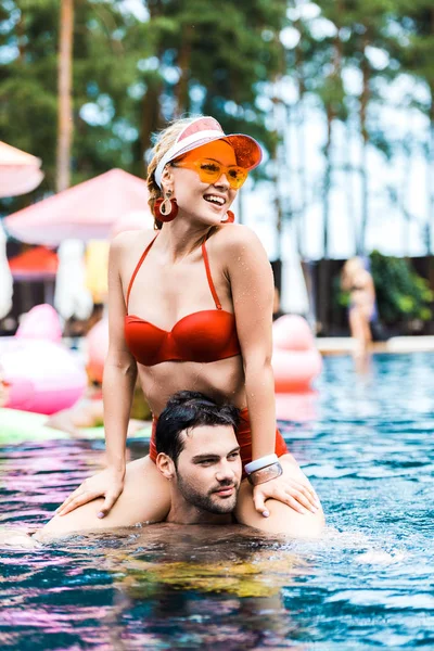 Smiling Woman Red Swimsuit Looking Away While Sitting Boyfriends Shoulders — Stock Photo, Image