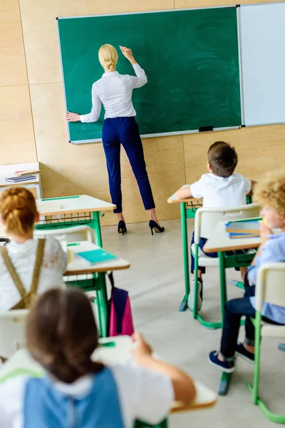 Rear View Kids Looking Teacher While She Writing Chalkboard — Free Stock Photo