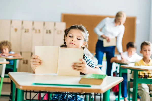 Schattige Kleine Schoolmeisje Lezen Boek Tijdens Les — Stockfoto