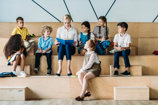 Bedårende Glade Skolebarn Som Hører Læreren Sin Mens Sitter Tribunen – stockfoto