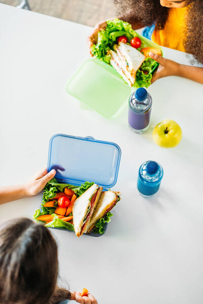 top view of little schoolgirls taking lunch together