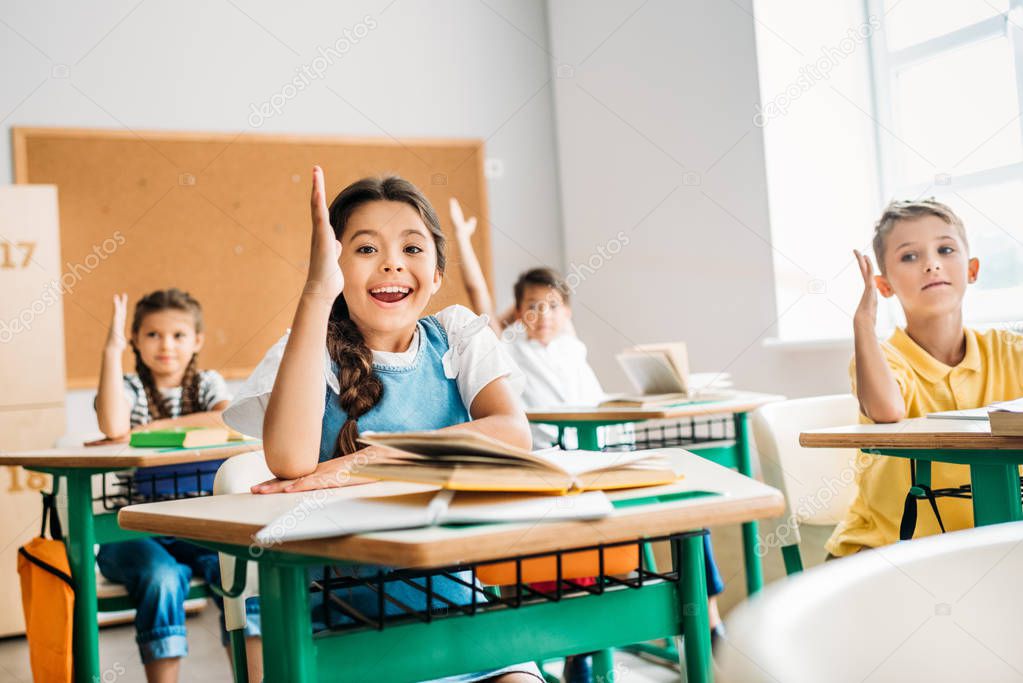 group of pupils raising hands to answer question during lesson