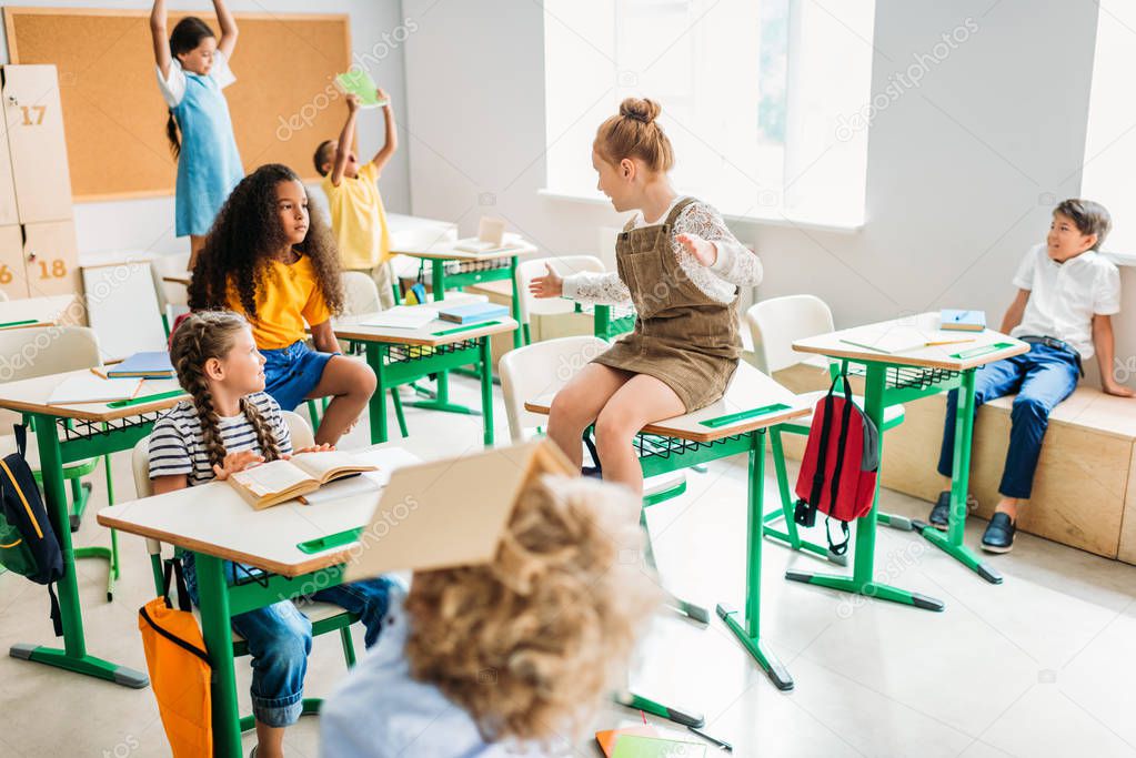group of schoolchildren having fun at classroom during break