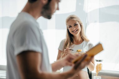 meyve salatası ile gülümseyen hamile eşi ve kocası evde mutfak kitap ile seçici odak