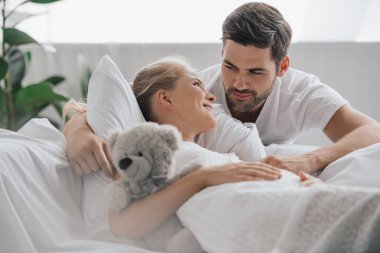 teddy ile beyaz Geceliği hamile kadın kanepede ayı ve yakınındaki tarafından evde kocası