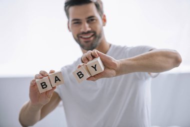 adam gösteren ahşap bloklar elinde evde bebek yazıt ile gülümseyen portresi