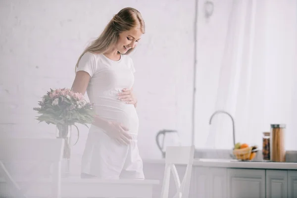 Happy Pregnant Woman Standing Table Bouquet Flowers Vase Home — Stock Photo, Image