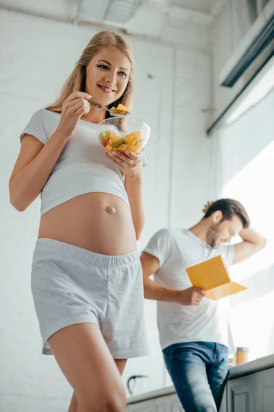 Selective Focus Smiling Pregnant Woman Eating Fruits Salad While Husband — Stock Photo, Image