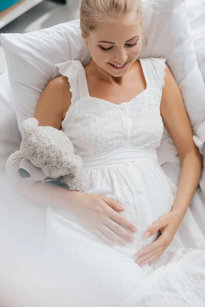 Översiktsbild Leende Gravid Kvinna Vitt Nattlinne Med Nalle Som Vilar — Stockfoto