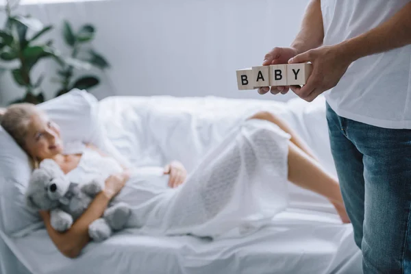 男の赤ちゃんを妊娠中の妻が自宅のソファーで休んでいる間レタリングで木製のブロックを保持のクロップ撮影 — ストック写真