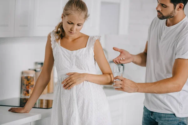 Zwangere Vrouw Witte Nachtjapon Met Ongemak Terwijl Echtgenoot Geneesmiddelen Glas — Stockfoto